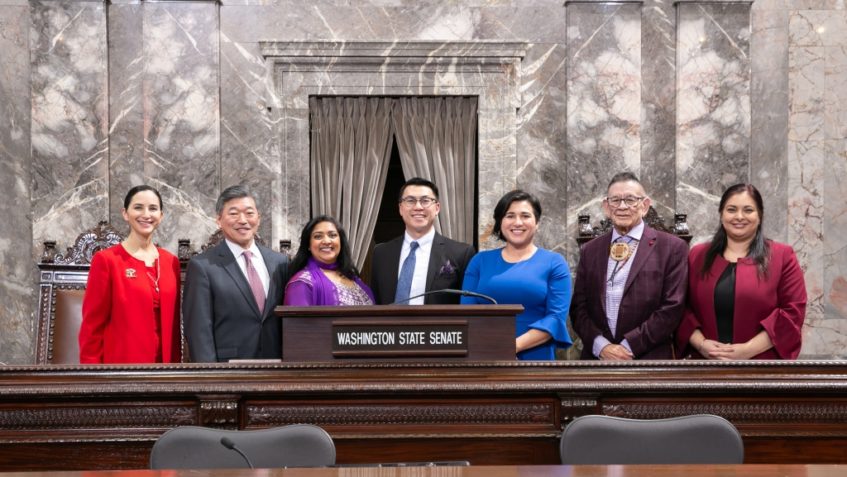 Members of the Senate Members of Color Caucus stand behind a podium on the Senate floor.