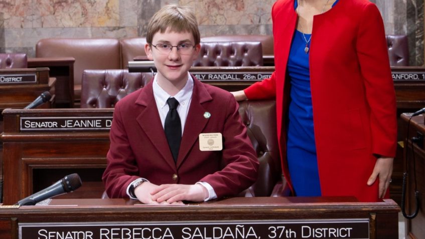 Sen. Saldana with Page Daniel Zipperer posing at the senator's desk on the Senate floor.