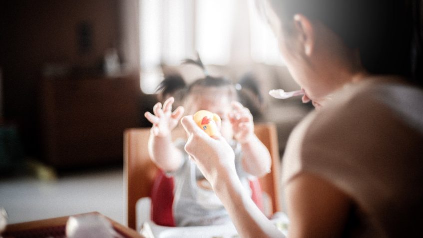 Woman feeding toddler.