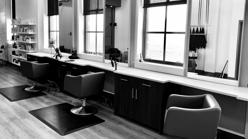 Black and white photo of three empty chairs in a hair salon.