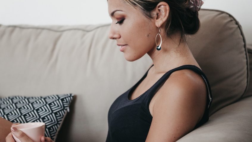 Woman sitting on sofa holding cup of coffee.