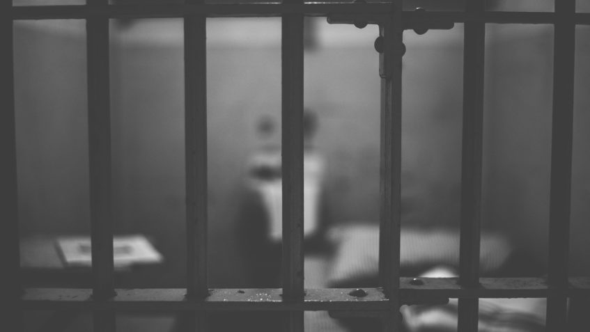 View looking into jail cell from outside the cell's bars.