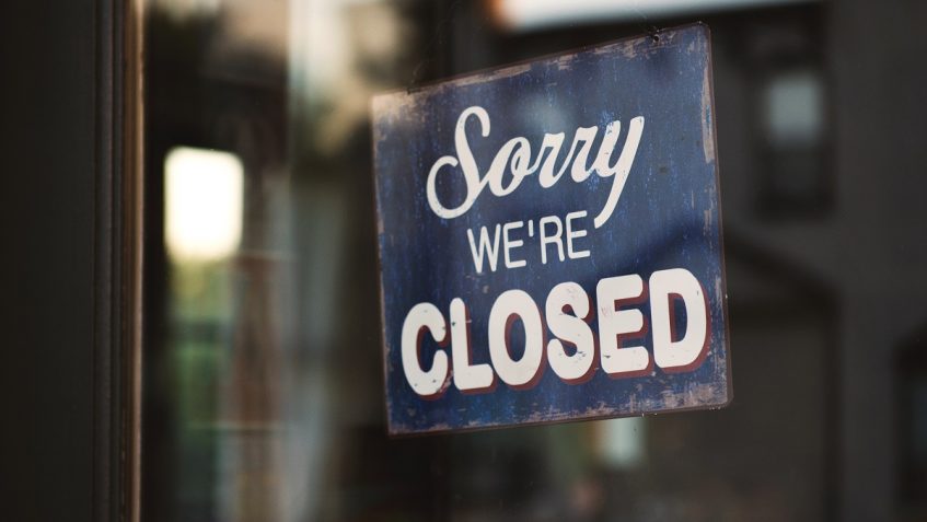 "Sorry we're closed" sign hanging in a window.