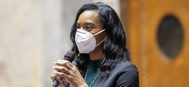 Senator T'wina Nobles wears a mask over her nose and face and speaks into a microphone from the senate floor in Olympia